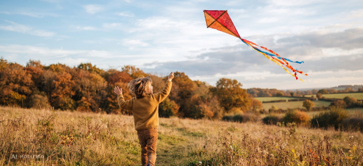Kind lässt einen selbst gebastelten Drachen im Herbst auf einer Wiese steigen